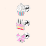 Silver kids flat back earrings with cupcake, cake, and bow designs on a pink background