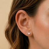 A close-up image of a girl wearing a pink. glittery love heart earring.