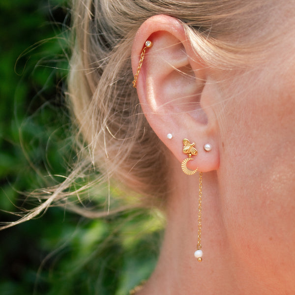 Woman's ear wearing with various gold and pearl earrings