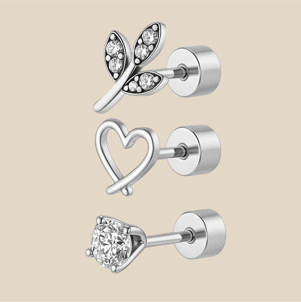 Set of silver earrings with heart, leaf, and round designs on a beige background