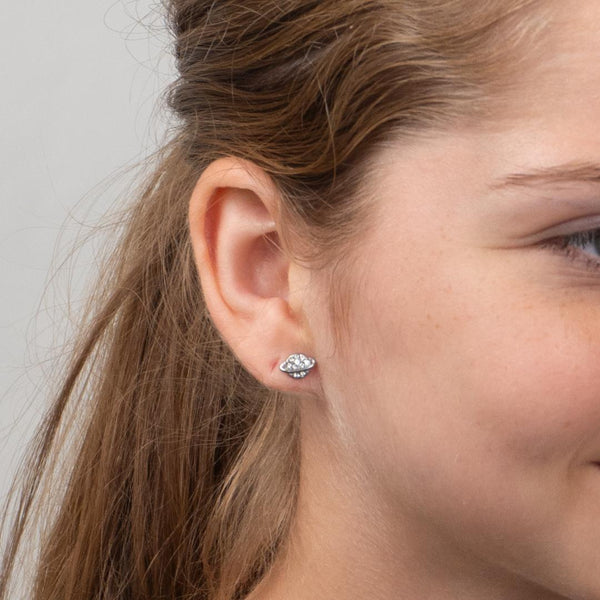 Close-up of a girl's ear wearing a diamond stud planet earring against a neutral background