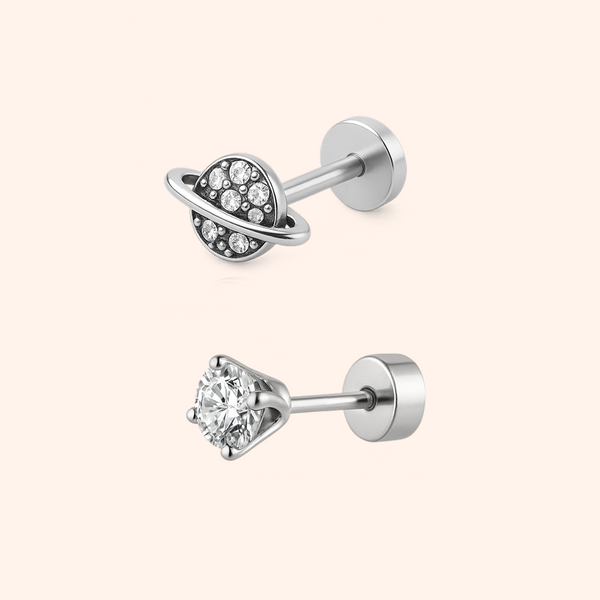 Two silver earrings with clear gemstones on a light pink background