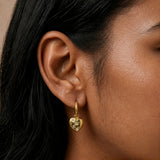 Close-up of model wearing Gold Cleo Chunky Heart Hoops with a polished heart charm and clear cubic zirconia detailing