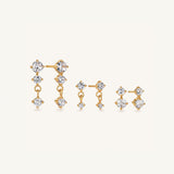 A set of gold-toned jewellery pieces with clear gemstones, including a large statement piece and two smaller matching earrings, arranged on a plain light background.