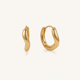 A pair of polished gold huggie hoop earrings shown on a clean, off-white background. One earring is displayed from a side profile, and the other is shown from a front-facing angle.