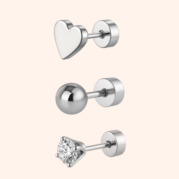 Set of three silver earrings on a pink background