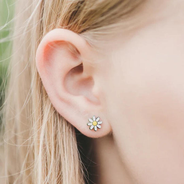 Close-up of a girl wearing a daisy flower earring.