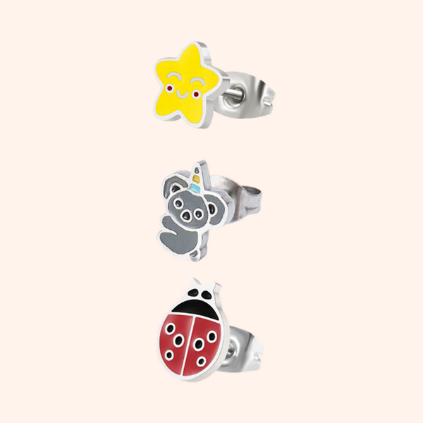 Set of three children's earrings with star, bear, and ladybug designs on a pink background.