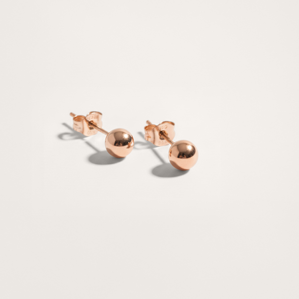Ball hypoallergenic stud earrings in rose gold finish on white background
