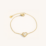 Gold bracelet with a heart-shaped charm on a white background.