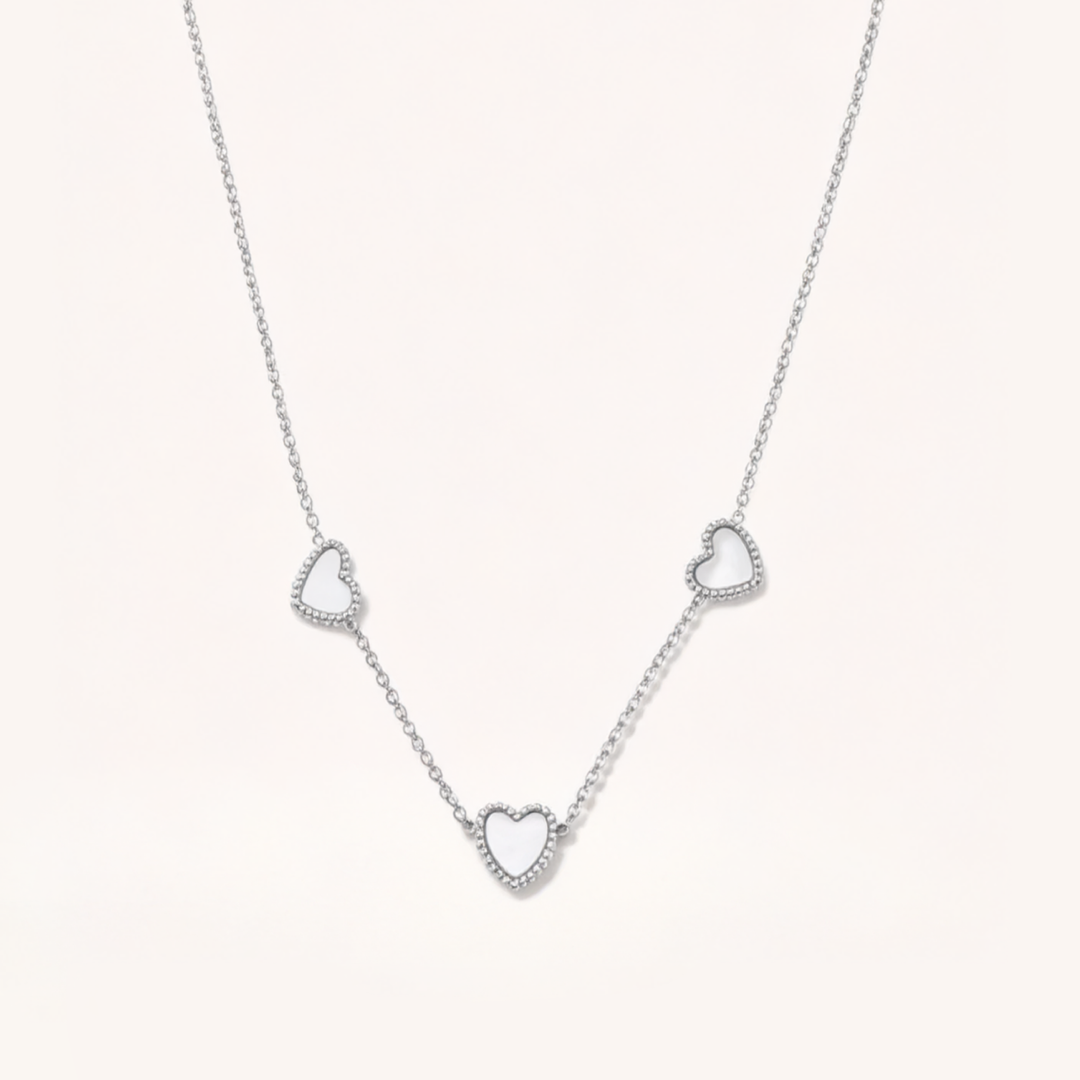 Silver necklace with heart-shaped pendants on a light gray background