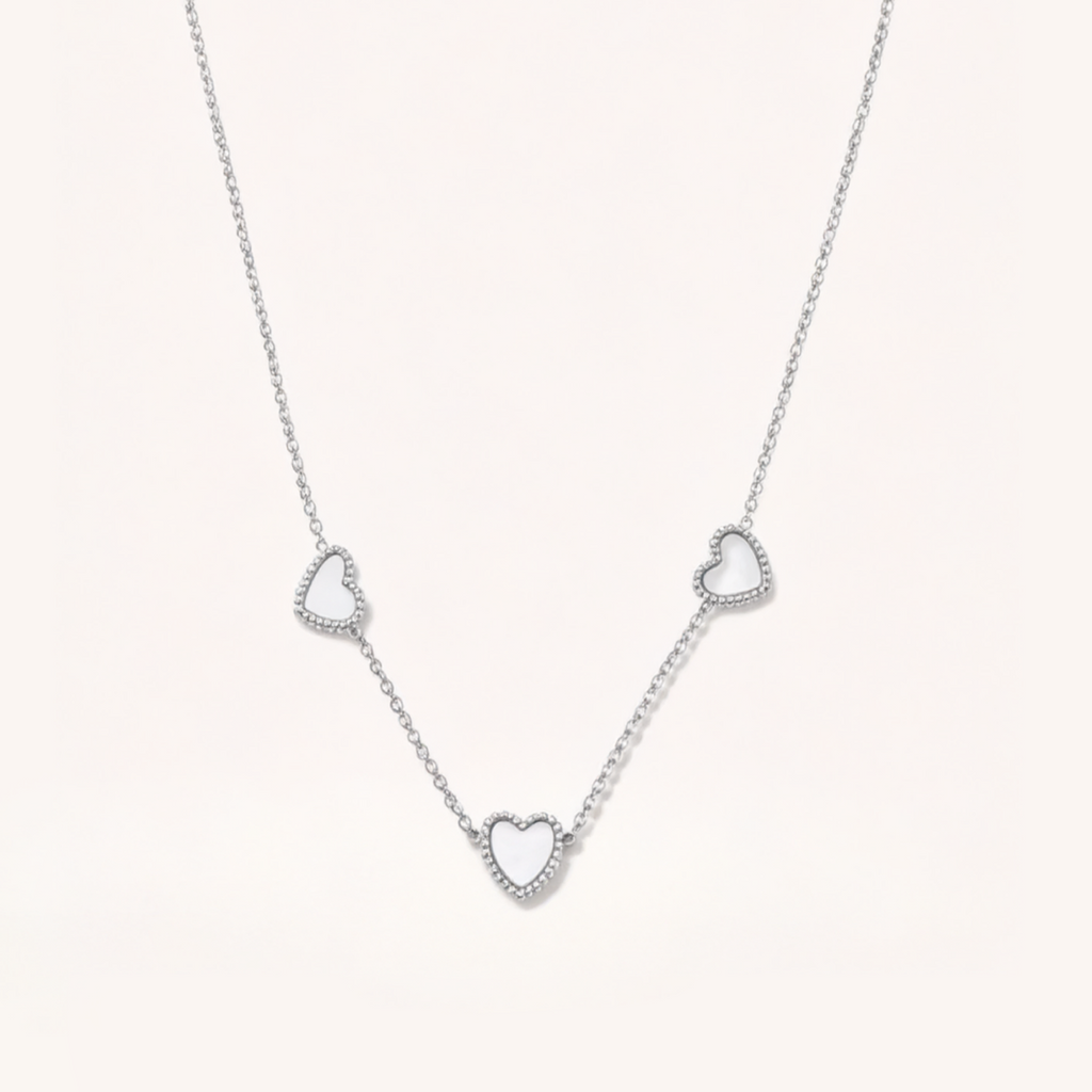 Silver necklace with heart-shaped pendants on a light gray background