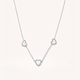 Silver necklace with heart-shaped pendants on a light gray background