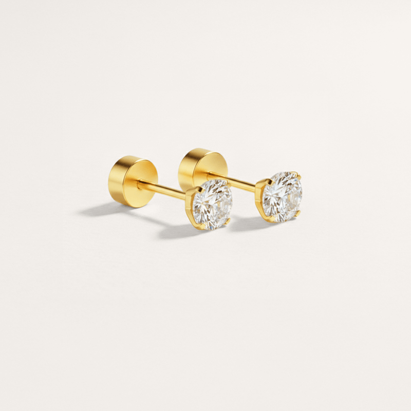 Gold stud earrings with clear gemstones on a light gray background