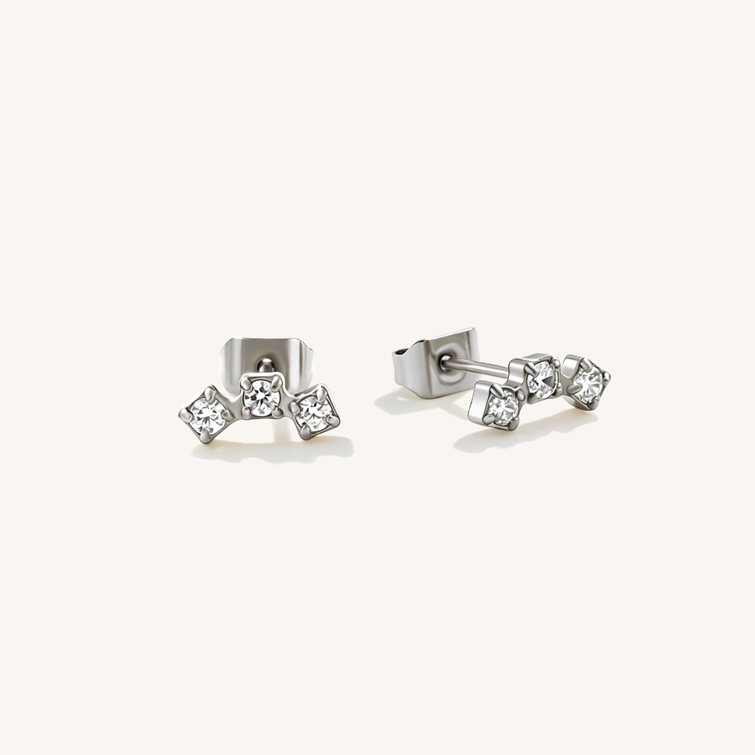 A pair of silver curved studs with 3 cubic zirconia pieces.