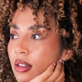 Close-up of a woman with curly hair showing butterfly studs