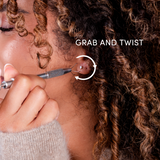 Close-up of a girl using the earring grabber, with text 'Grab and Twist' on a blurred background.