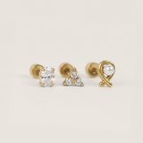 Three gold earrings with gemstones on a light beige background