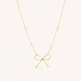 Gold bow-shaped pendant necklace on a white background.