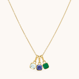 Gold necklace with three colored gemstones on a white background