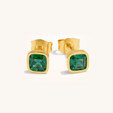 Gold earrings with green gemstones on a white background