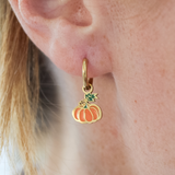 Gold earring with a pumpkin charm worn by a girl.