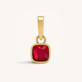 Gold pendant with a red gemstone on a white background