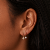 A woman wearing 1 gold earring designed to look like 2 earrings with cubic zirconia and a north star.