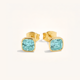 Gold stud earrings with blue gemstones on a white background