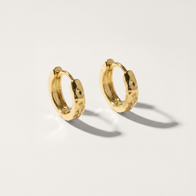 Hammered hypoallergenic huggie earring in gold on white background
