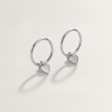 Mini heart huggie hypoallergenic hoop earrings in silver on white background
