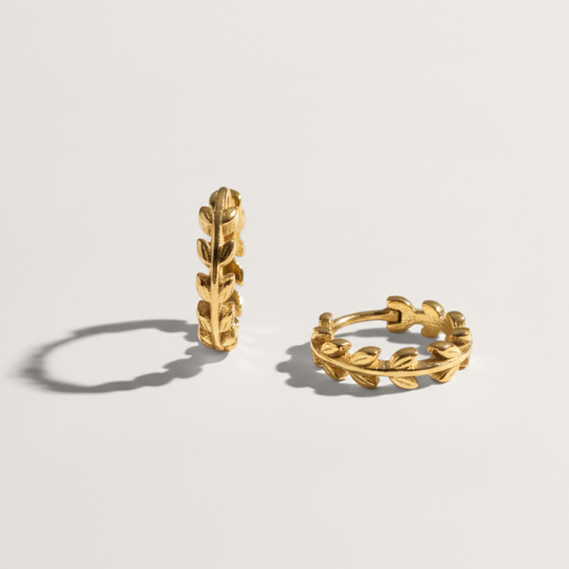 Olive leaf hypoallergenic huggie earring in gold on white background
