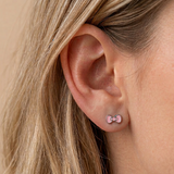 A girl wearing a pair of pink bow flat back earrings.
