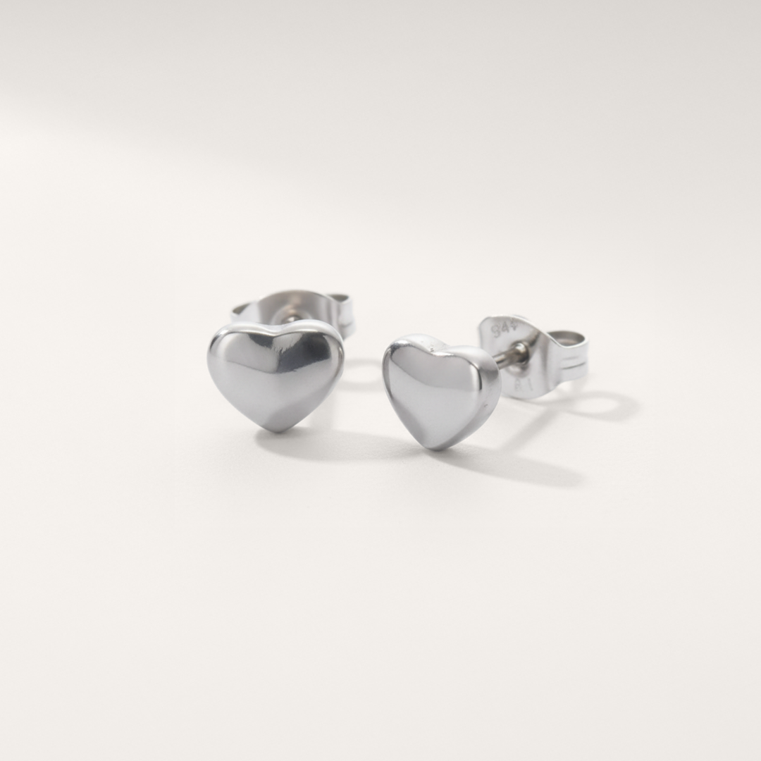 Rounded heart hypoallergenic earrings in silver on white background