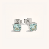 Pair of silver stud earrings with light blue gemstones on a white background