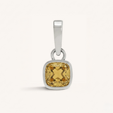 Silver pendant with a yellow gemstone on a white background