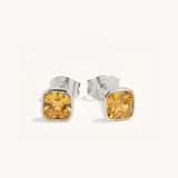 Silver stud earrings with yellow gemstones on a white background
