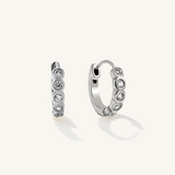 A pair of silver hoop earrings with cubic zirconia bits in the middle.
