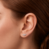 A lady wearing silver stud earrings with three crystals. 