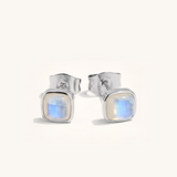 Pair of silver stud earrings with a moonstone-like gemstone on a white background