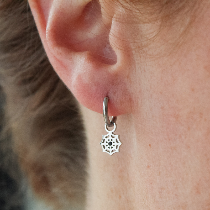 Close-up of a girl wearing a silver mystic web hoop earring.