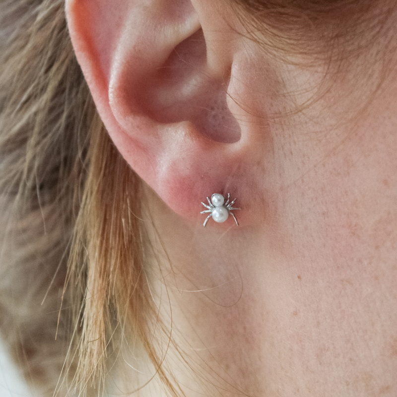 Close-up of a girl wearing a silver spider earring with pearls.