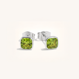 Silver stud earrings with green gemstones on a white background