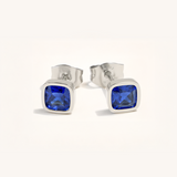 Silver stud earrings with sapphire gemstones on a white background
