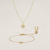 Gold jewelry set with star-shaped pendants on a light beige background