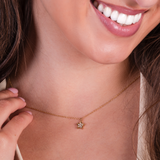 Close-up of a woman wearing a gold necklace with a star-shaped pendant.